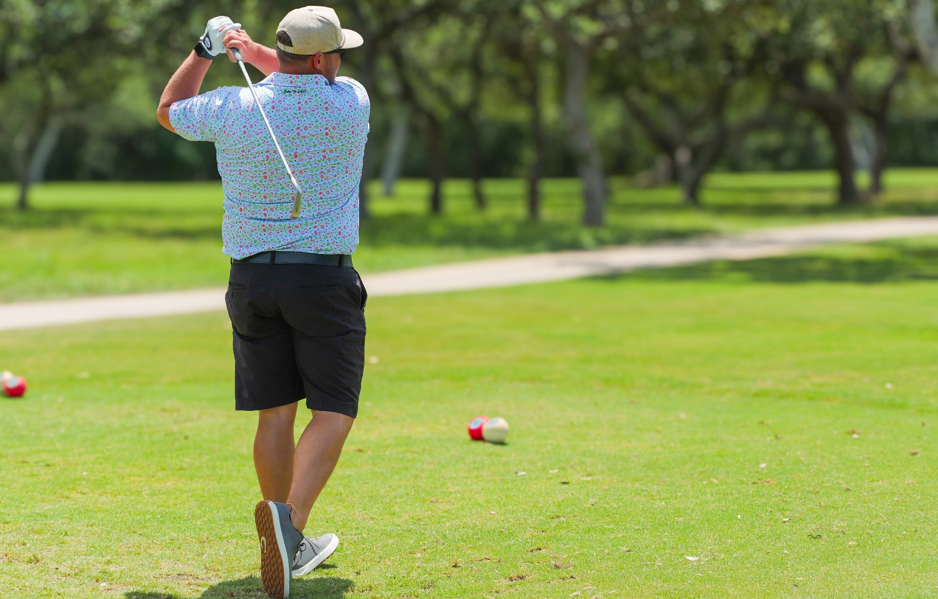 Man playing golf on a green course with trees in the background