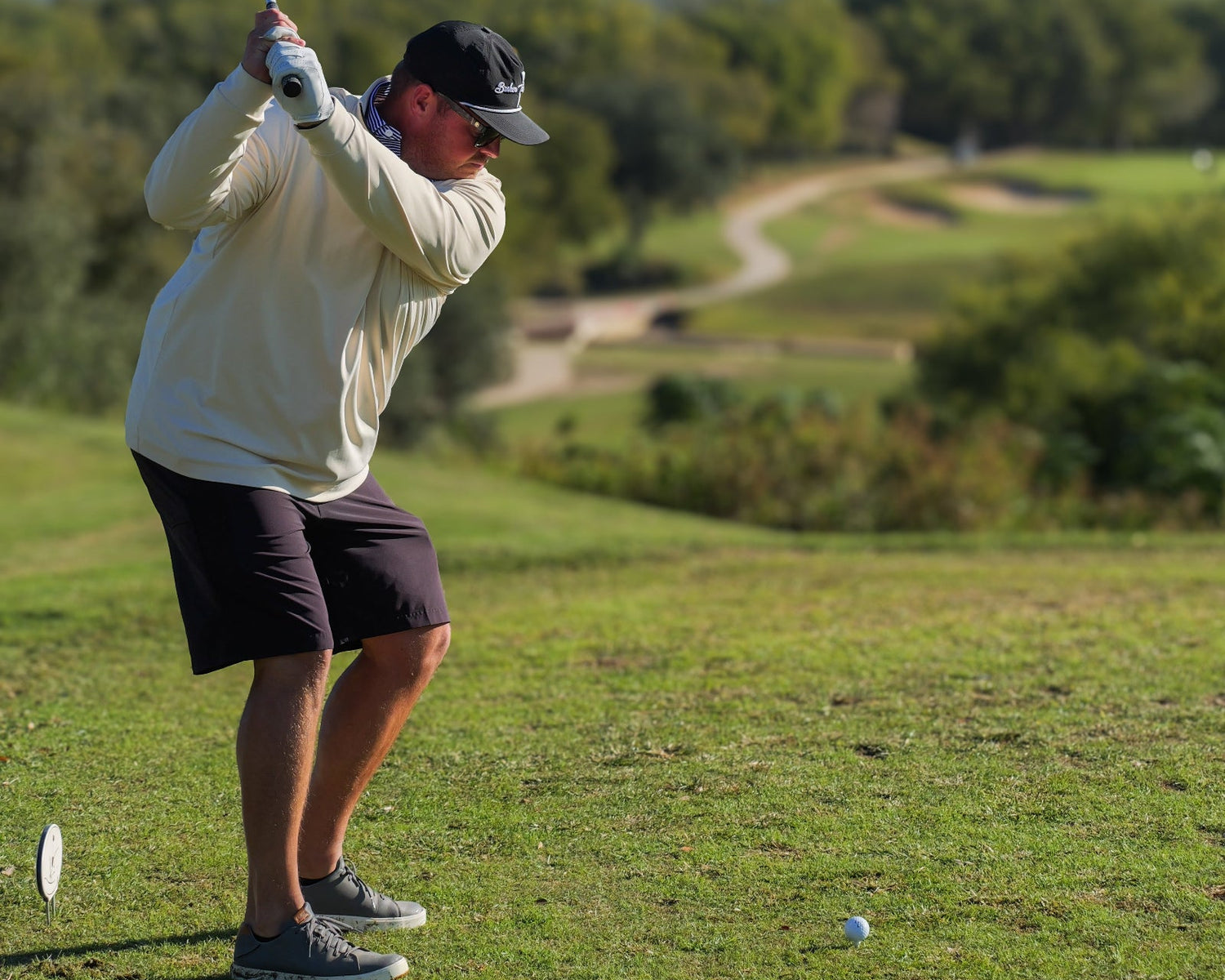 Man playing golf on a green course with trees in the background
