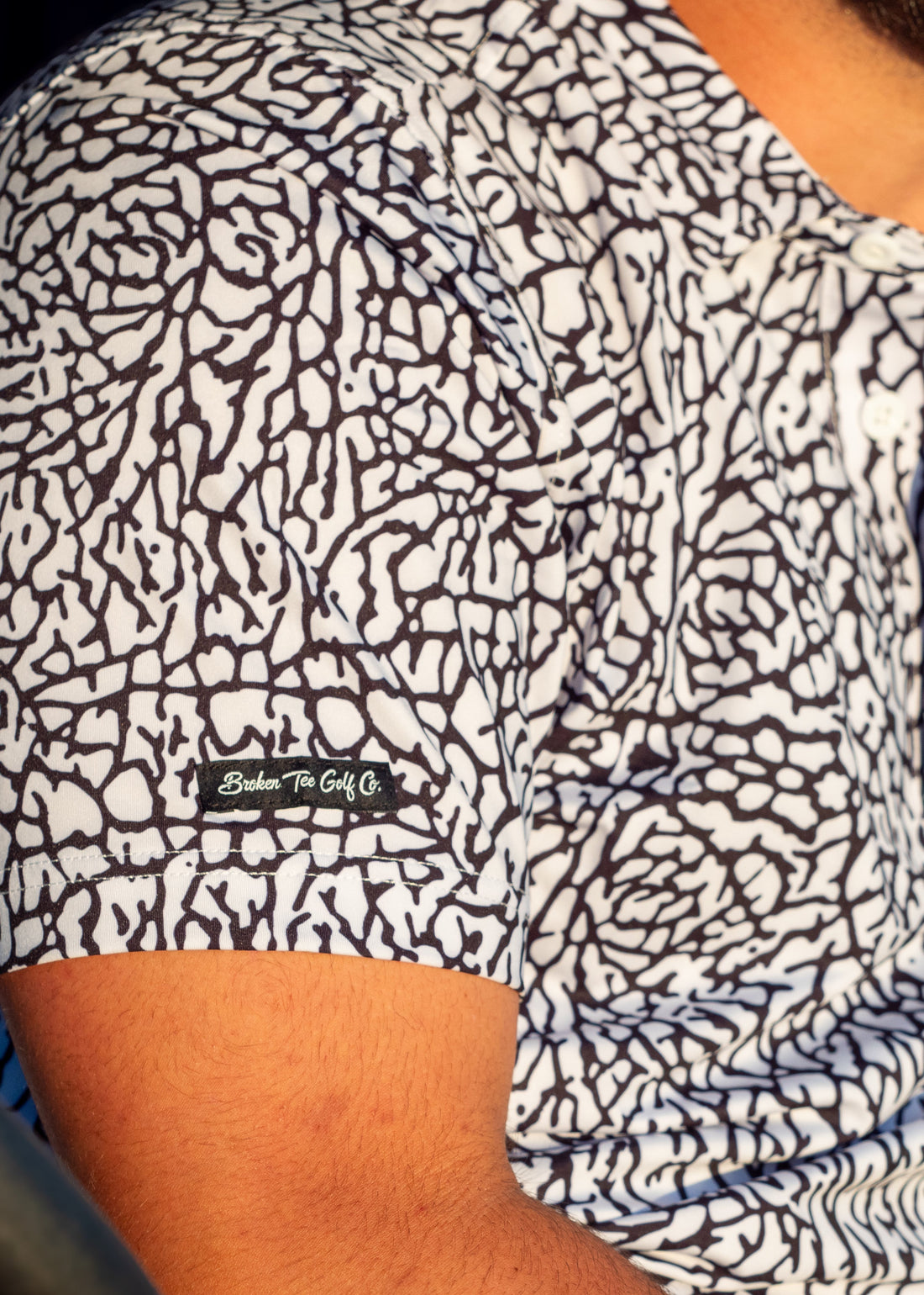 Person wearing a patterned shirt with a visible brand logo.