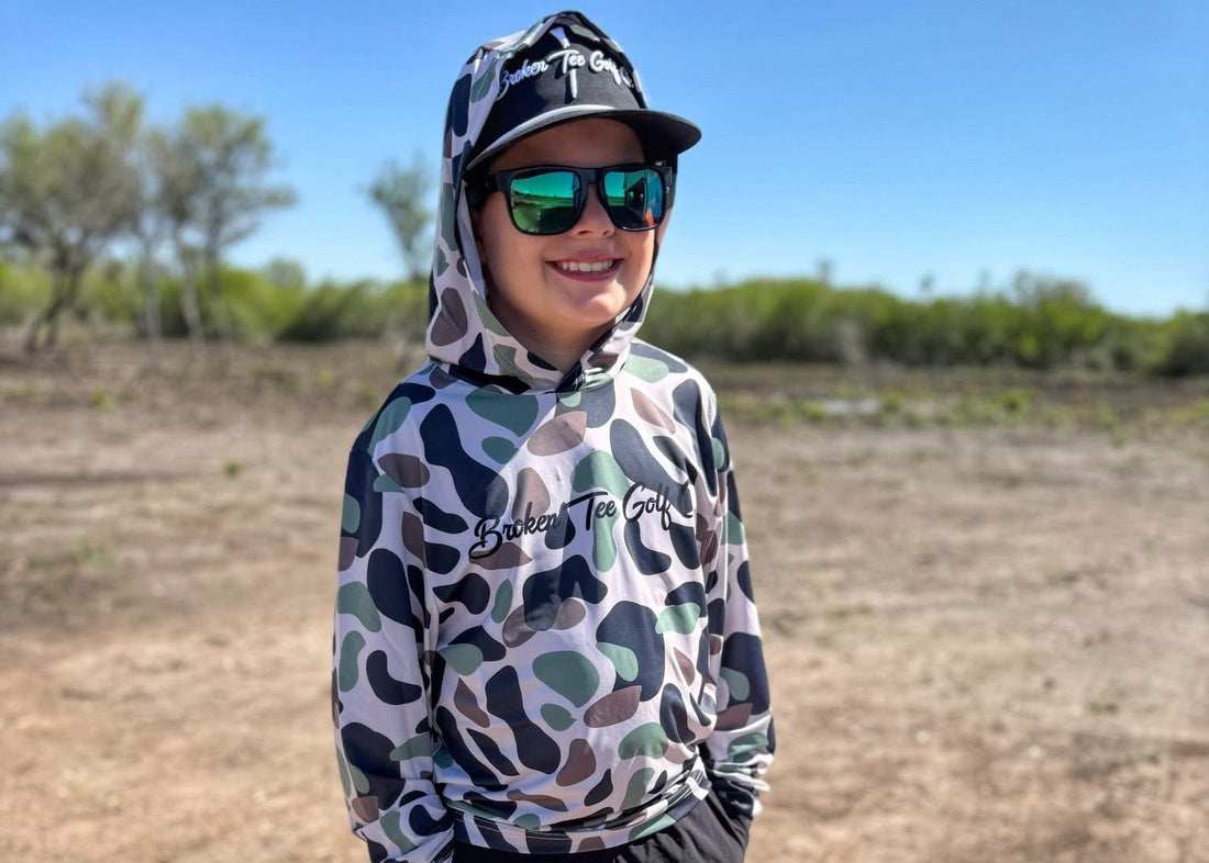 Person wearing a camouflage hoodie and sunglasses in an outdoor setting